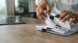© onephoto - Hands sort clipped paper documents beside laptop on wooden desk, organizing pages and reviewing file bundles for office records management, document handling, filing workflow with copy space.