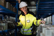© amorn - Woman worker using digital tablet working  and inspecting at shelves of electronic equipment parts in warehouse