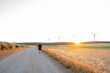 © Nazareno - Runner exercising along countryside road with wind turbines at sunset