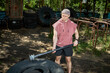 © TrueFrame Collective - Young adult Caucasian man training with weighted mace beside tractor tire in outdoor gym, building strength and endurance. Ideal for fitness marketing, bootcamp promotion, functional workout content