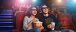 © itlada - Couple wearing glasses watching cinema movie with popcorn and soda drink amidst vivid blue and red projector lights for movie premiere entertainment concepts for commercial technology