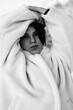 © shymar27 - Black and white winter portrait of a peaceful young woman wearing a cozy white teddy bear coat with eyes closed.
