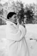 © shymar27 - Black and white winter portrait of a peaceful young woman wearing a cozy white teddy bear coat with eyes closed.