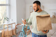 © Pixel-Shot - Young man with paper bag using mobile phone at home. Food delivery service