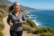 © Formoney - A person runs on a path by the coast. Waves crash against the rocks below. Green hills rise on one side, and the sun shines in a clear sky.