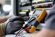 © The Little Hut - Electrician using a multimeter to test electrical panel wiring and circuit breakers in industrial setting