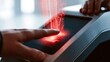 © FauziNh - Finger scan on futuristic device with red biometric light waves