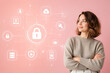 © Anastasiia - A young woman in a beige sweater looks thoughtfully at a digital interface displaying security icons against a pink background.
