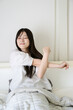 © Yamatatsu - ベッドでストレッチをする日本人女性