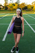 © Manu Prats/Stocksy - Active female carrying a yoga mat across a track field at sunset
