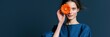 © Andrii Zastrozhnov - Young woman holding orange gerbera flower to eye in blue dress on dark background for fashion banner and editorial design