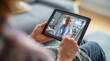 © Justlight - Closeup of caregivers hands navigating a telehealth video call on a tablet while the patients face is gently blurred.