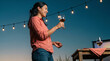 © Nei Mar - Young woman enjoying a drink at a backyard movie night party