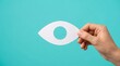 © BrilliantPixels - A hand holding a paper eye cutout for vision care and glaucoma awareness.