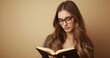 © VolumeThings - Attractive lady with glasses reading a book against a cream backdrop.