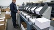 © Xenia - Female operator working at an industrial paper collating machine in a printing factory. Large stacks of white paper sheets on a conveyor belt. Commercial print shop production