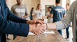 © Luminostock 54 - leadership development nonprofits volunteer concept. Two people shaking hands in a casual meeting setting with others in background