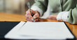 © peopleimages.com - Documents, signature and hands of woman in office for health insurance claim with application. Paperwork, signing and person with medical consent form, survey or consultation policy in workplace.