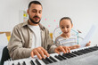 © Pixel-Shot - Teenage girl with tutor playing synthesizer at home