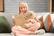 © Pixel-Shot - Little Muslim girl in hijab with teddy bear reading book at home