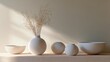 © Anastasia - Group of five white vases and bowls arranged on a white surface against a beige wall.