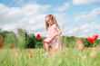 © Westend61 - Little girl walking in a summer poppy field holding a flower