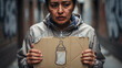 © DEVRIESTHOMAS MAARTE - Homeless woman holding a cardboard sign with a baby bottle drawing. Desperate mother pleading for infant supplies in a dark alley. Poverty and social welfare concept for charity campaigns.