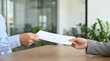 © Kaff - Close-up of a businessman handing a contract document to another person at an office desk