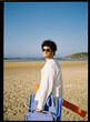 © Alvaro Lavin/Stocksy - Young man carrying beach chair at ocean vacation