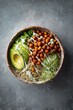 © Iftikhar alam - Colorful plant-based bowl with quinoa, avocado, greens, and chickpeas served on a stone backdrop in a casual dining setting