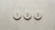 © MstUmme - Minimalist concept of 123 steps represented by three circular stone discs with numbers on a textured concrete surface