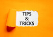 © Dzmitry - Tips and tricks words symbol. Concept words Tips and tricks on beautiful white paper. Beautiful orange background. Business tips and tricks motivational support concept. Copy space.