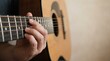 © Reni - Close up of a hand playing chords on an acoustic guitar
