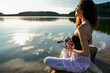 © ADDICTIVE STOCK - Woman meditating by a calm lake at sunrise for balance