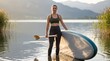 © Thiago - Portrait of a young woman standing in water holding a stand up paddleboard and