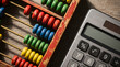 © SIMANG - Colorful abacus and electronic calculator placed side by side on wooden surface