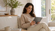 © Vyatcheslav - Young woman using digital tablet on white sofa. Happy female browsing online in bright modern living room. Leisure and technology concept