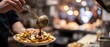 © Hammad - Hot brown gravy being poured from a metal ladle onto crispy french fries topped with white cheese curds in a professional street food kitchen with visible rising steam