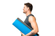 © luismolinero - Young sport man going to yoga classes while holding a mat over isolated chroma key background laughing in lateral position