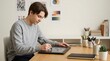 © Konstantin - Teenage boy using a digital drawing tablet at a desk. Young digital artist sketching with a stylus in a creative workspace. Graphic design concept