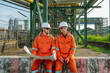 © BESTIMAGE - Team industrial workers inspecting petroleum engineering in oil refinery inspection check collaboration at fuel industry Two male wear coverall with blueprint for work near petrol tubing site