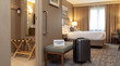 © alex - A grey suitcase stands next to a bench displaying an accessible room sign, near a wall support rail in a hotel bedroom entrance.