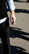 © Mirivox - Man holding a cigarette, dressed in a shirt and sweater, with shadow cast on asphalt, representing adult habit and lifestyle