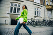© Jacob Lund - Female entrepreneur walking with laptop in vibrant city setting
