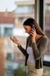 © gzorgz - Smiling businesswoman using phone in office