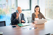 © gzorgz - Two mid-aged business people working together on a laptop in a modern office