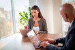 © gzorgz - Two mid-aged business people working together on a laptop in a modern office