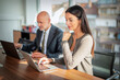 © gzorgz - Two mid-aged business people working together on a laptop in a modern office