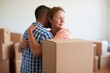 © The Little Hut - Happy Couple Embracing Surrounded by Moving Boxes in a New Home