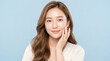 © Shawon - Close up portrait of beautiful young asian woman with clear skin touching cheek gently on light blue background studio beauty fashion photoshoot cosmetic skincare healthy glow model.